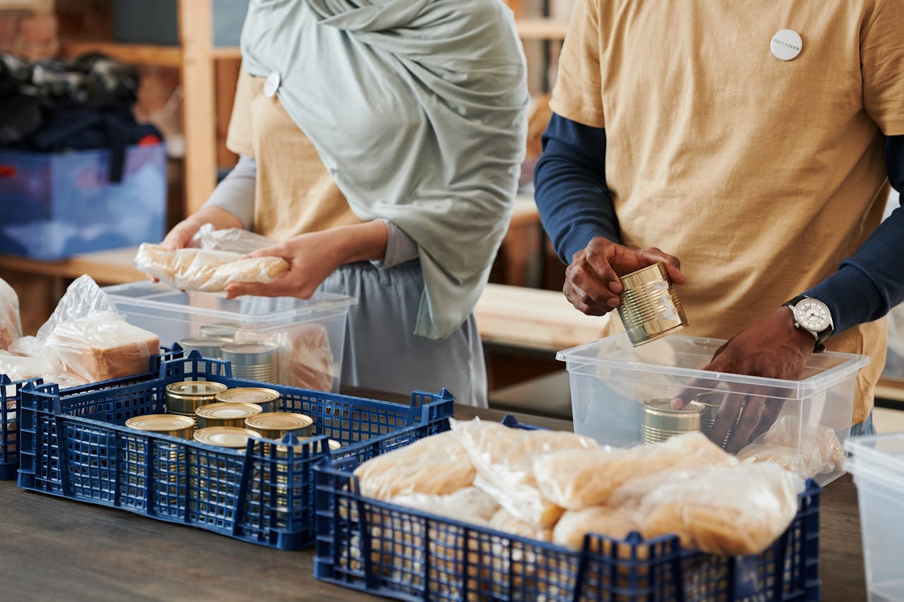 services-03 Adults sorting food donations in containers for charity. Community service effort indoors.